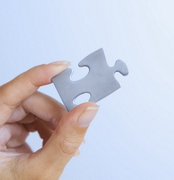 Puzzle Piece Between Woman's Fingers